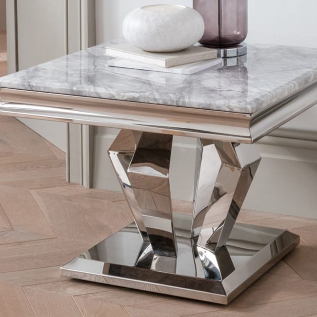 lavish_ A modern side table with a marble top and a reflective angular base, such as the Arturo Lamp Table, serves as stylish home decor in a room boasting southport herringbone wood flooring.