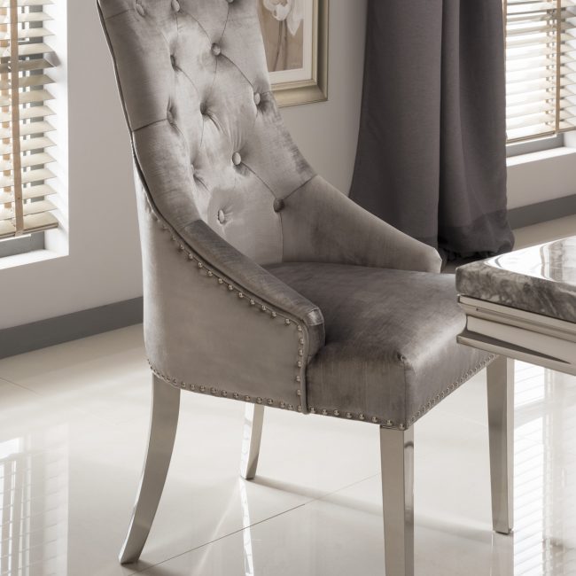lavish_ The Belvedere Knockerback Dining Chair, with button tufting and silver nailhead trim, set in a modern room with natural light, enhances the home decor through its sophisticated design.