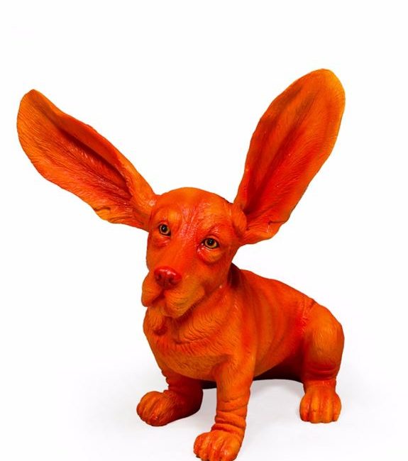 lavish_ An orange statue of a stylized dog with exaggeratedly large ears, perfect as unique home decor.