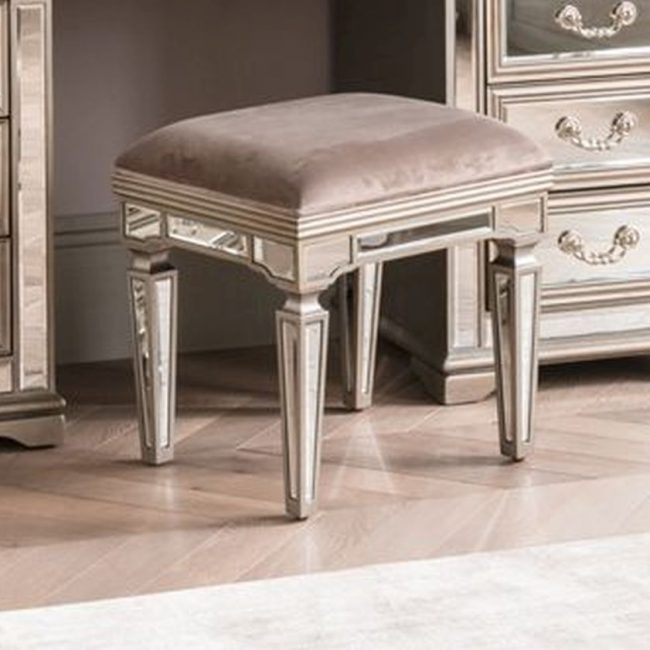 lavish_ An elegant Jessica Dressing Table Stool with a plush cushion located next to a southport dresser with reflective accents.