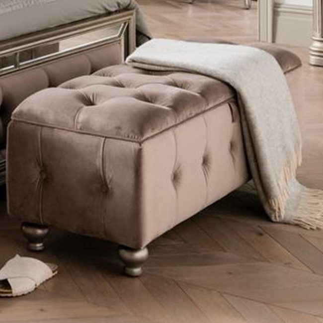 lavish_ Elegant Jessica storage ottoman with a gray throw blanket and a pair of slippers on a wooden floor.