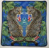 lavish_ Two Juniper Malek Leopards Cushions mirrored against a backdrop of tropical foliage on a decorative square fabric, perfect for Southport home decor.
