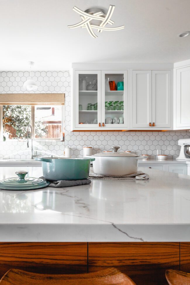 lavish_ Modern kitchen interior with white cabinetry and marble countertops, featuring a hexagonal tile backsplash and cookware on the counter. The Harvey 5 Light Ceiling, 3 Step Dimming, 5 x 12W LED, 4000K, 3792lm, White-inspired home decor enhances the space's aesthetic appeal.