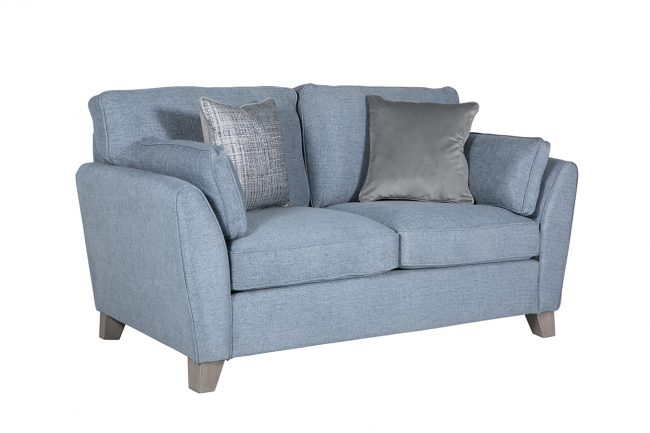 lavish_ A blue fabric loveseat with cushions on a white background, reflecting Southport-inspired home decor.