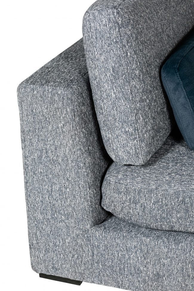 lavish_ Close-up of a gray fabric sofa with a blue cushion.